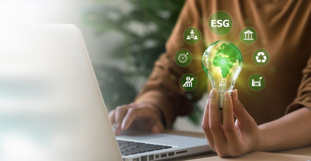 Empresária segurando lâmpada com ícones de ESG e laptop ao fundo