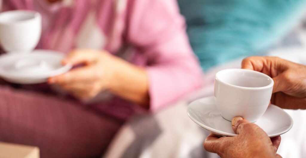 Duas pessoas compartilhando uma conversa enquanto seguram xícaras de café.