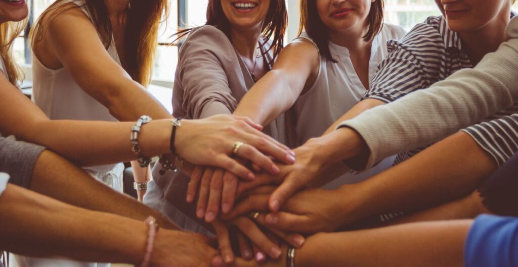 Grupo de mulheres unidas em um círculo, representando conexão, acolhimento e crescimento pessoal.