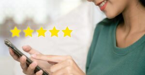 Mulher usando smartphone com cinco estrelas flutuantes simbolizando satisfação do cliente.