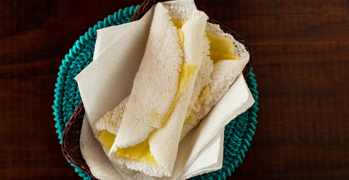 Tapioca recheada com queijo servida em um cesto de palha sobre uma mesa rústica, representando um negócio tradicional inovador.