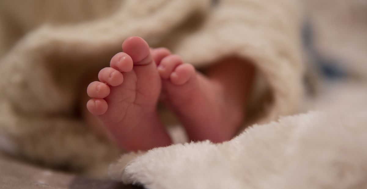 Pés de um bebê reborn envoltos em manta macia, representando realismo e delicadeza dos bonecos hiper-realistas.