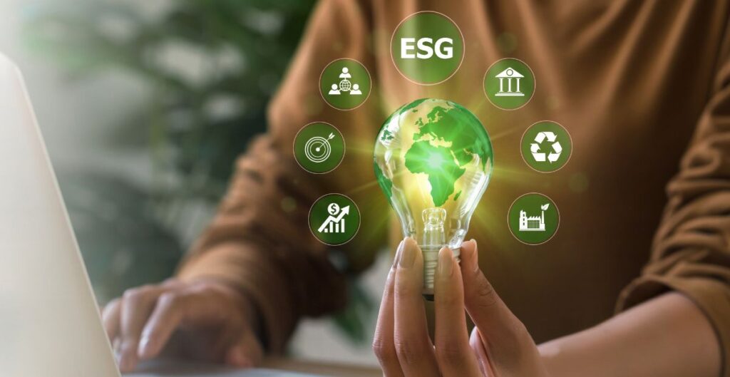 Pessoa segurando lâmpada com imagem do planeta e ícones de sustentabilidade e ESG, representando práticas empresariais responsáveis.
