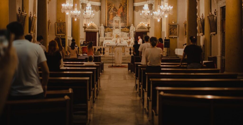 Famílias com crianças participando de uma missa em igreja católica, representando o desafio e a importância da presença infantil nas celebrações religiosas.