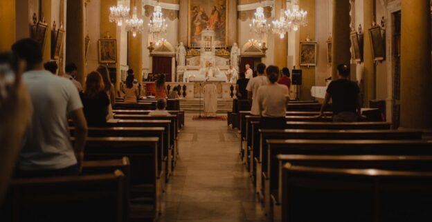 Famílias com crianças participando de uma missa em igreja católica, representando o desafio e a importância da presença infantil nas celebrações religiosas.