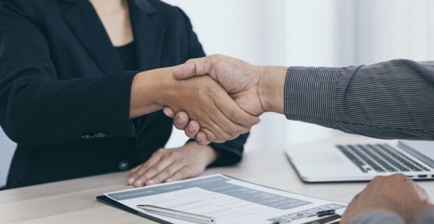 Aperto de mãos entre recrutador e candidato, simbolizando contratação de profissionais alinhados às novas tecnologias e tendências do mercado.