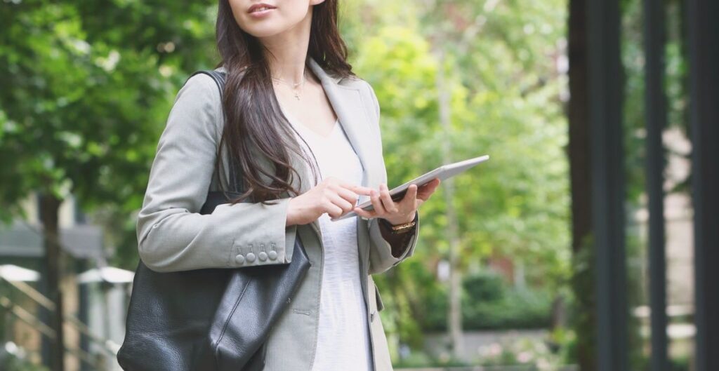 Mulher com look profissional elegante usando tablet em ambiente externo corporativo