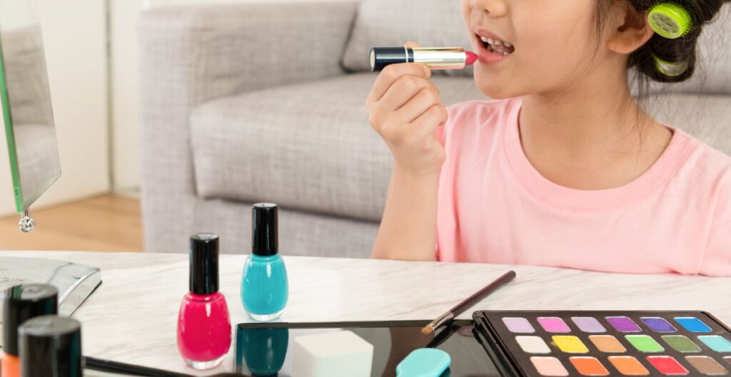 Criança se maquiando sozinha com batom e cosméticos em casa.