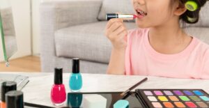 Criança se maquiando sozinha com batom e cosméticos em casa.