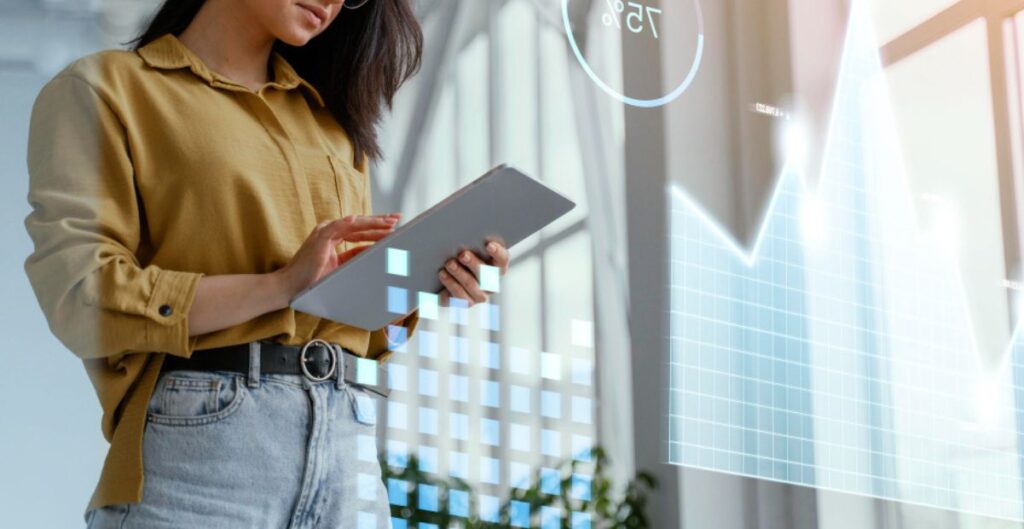 Mulher usando tablet com gráficos digitais e dados projetados no ar